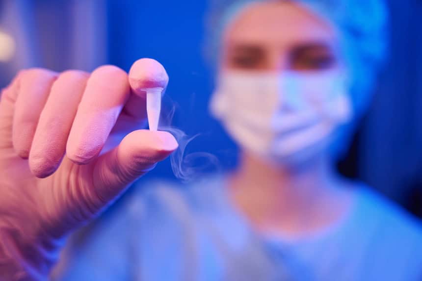 A lab scientist holding a vial of a frozen embryo